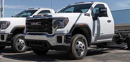 An image showing a white GMC Sierra Cab & Chassis truck in a parking lot.
