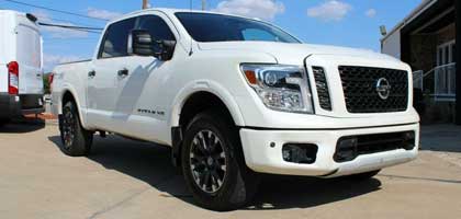 An image showing a white Nissan Titan in a parking lot.