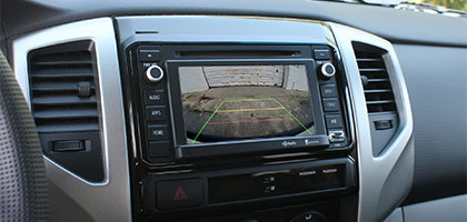 An image showing the original in-dash monitor of a vehicle. On the screen is the view from a backup camera that has been added.
