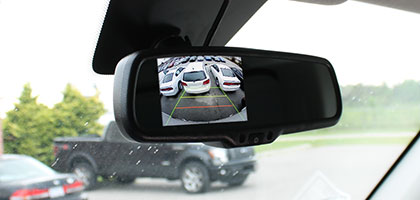 An image showing the rear view mirror of a vehicle. The mirror has an LCD screen built in to display video from a camera when the vehicle is shifted into reverse.