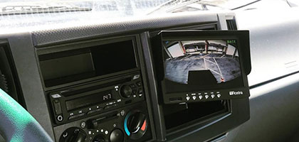 An image showing a large LCD monitor installed onto a vehicle dashboard. The monitor powers on automatically to display video from a camera when the vehicle is shifted into reverse.