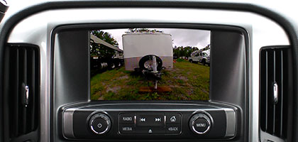 An image showing the factory in-dash monitor of a truck. On-screen is an image showing the truck backing up to a trailer.