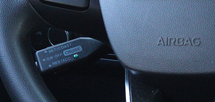 An image showing a cruise control switch through the opening in a steering wheel
