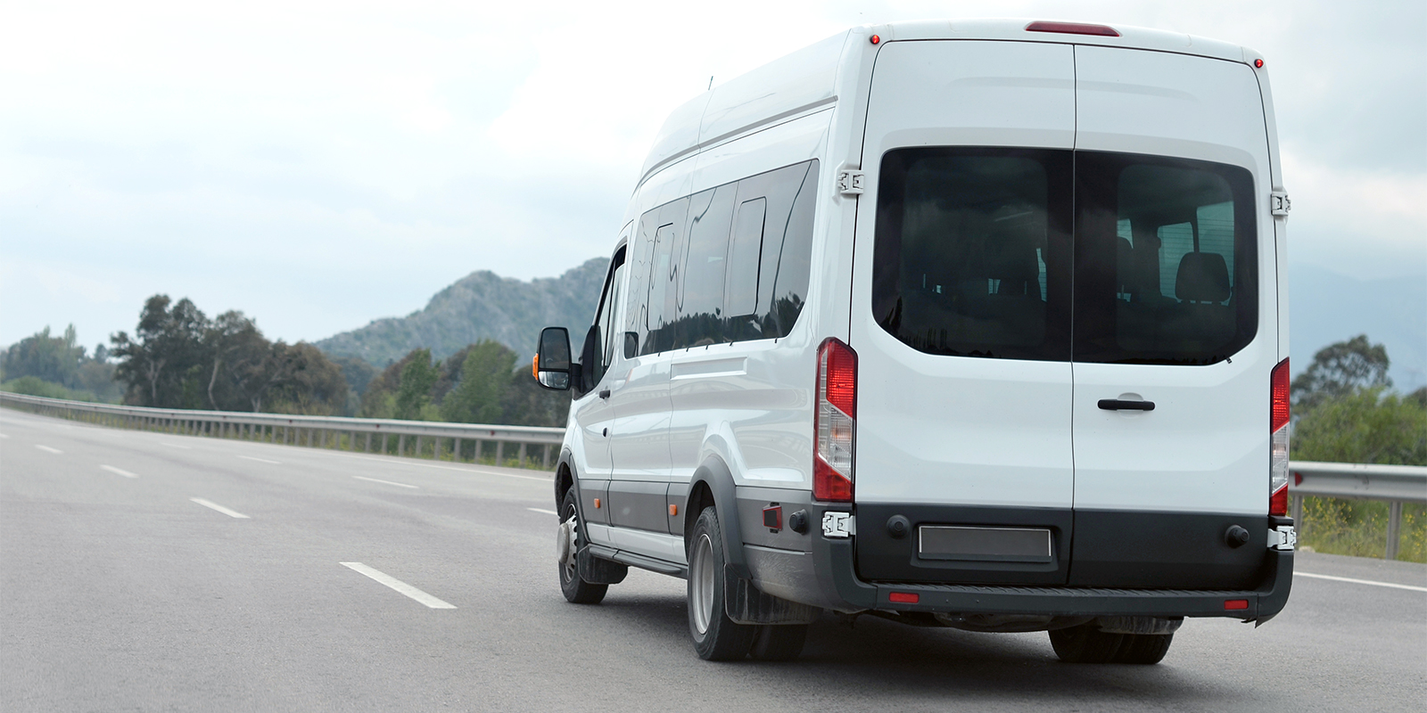 An image of a work van travelling along a highway. Attached to the side of the van are the sensors included with the Rostra 250-1930 kit for detecting vehicles in the van's blind spot.