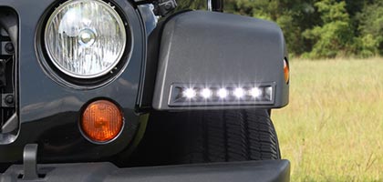 An image showing the front of a Jeep Wrangler. The focus of the image is on the front fender flare which includes Rostra's LED DRL system installed into the face of the fender.