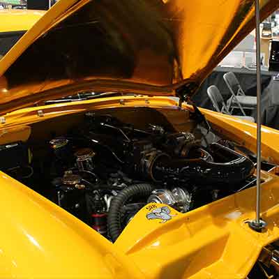 Engine compartment of a classic car with a carburetor showing how the Global Cruise universal cruise control system is installed.