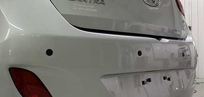An image showing the rear bumper of a vehicle. Four ultrasonic parking sensors are flush-mounted in the bumper.