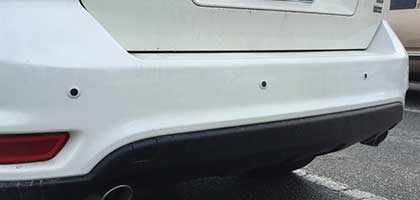 An image showing the rear bumper of a vehicle. Four ultrasonic parking sensors are flush-mounted in the bumper.