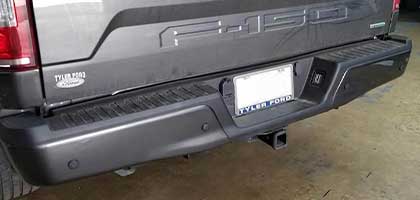 An image showing the rear bumper of a truck. Four ultrasonic parking sensors are flush-mounted in the bumper.