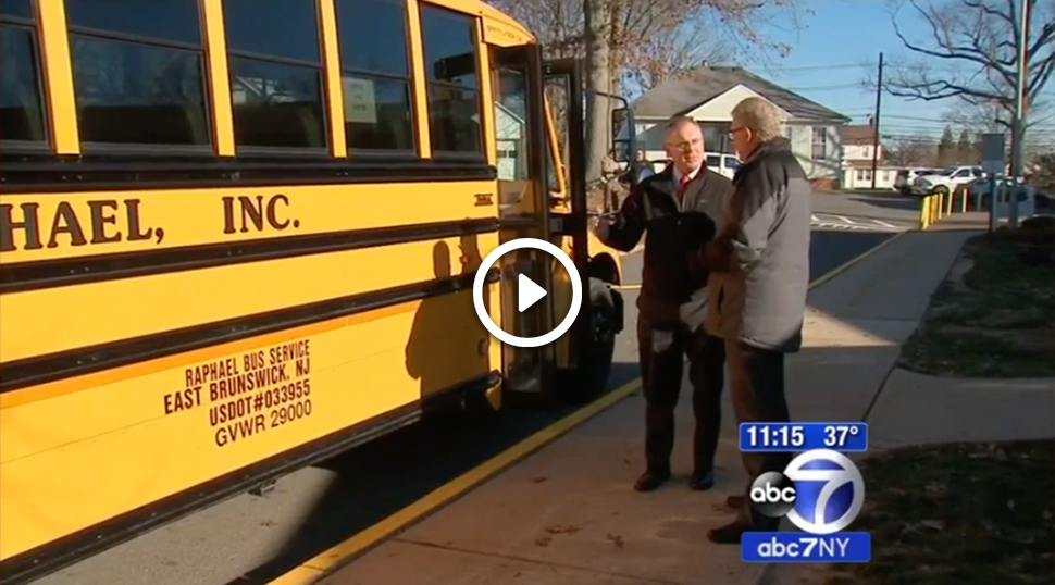 An image showing two men standing beside a bus talking. The image is from an original report aired by ABC 7 regarding the Rostra Student Detection System.