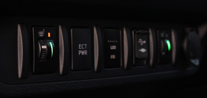 An image showing the dashboard of a Toyota vehicle. The image features the control switches from Rostra's Toyota-specific seat heaters which are both illuminated.