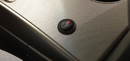 An image showing the control switch of a vehicle seat heater installed into the center console of a vehicle. The seat heater is powered on and a small red LED is illuminated