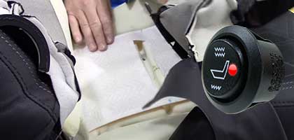 An image showing a person installating a seat heating element into the seat from an automobile.