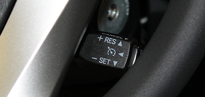 An image showing a cruise control switch through the opening in a steering wheel